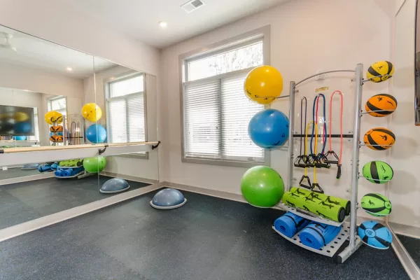 Open yoga and barre studio equipped with medicine balls, yoga mats, yoga balls, and a large mirror with a barre.