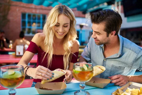 A couple eating tacos and smiling at a restaurant